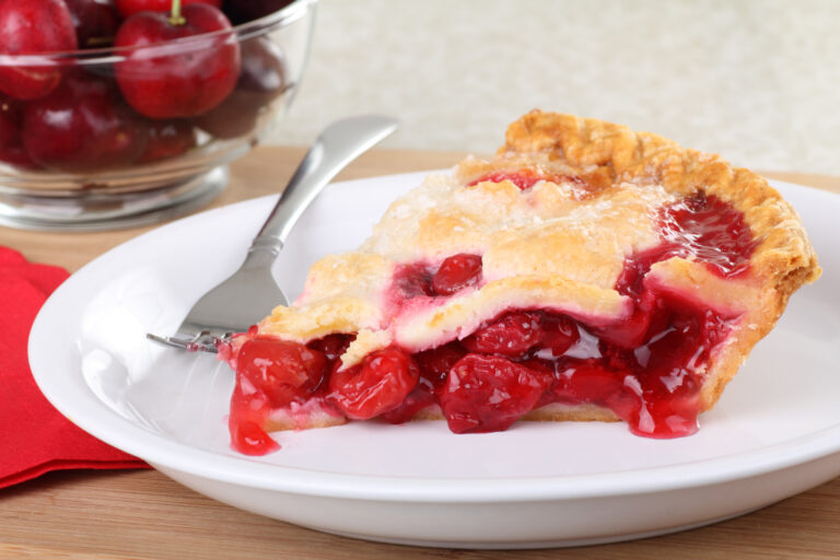 Slice of cherry pie on a plate with a fork