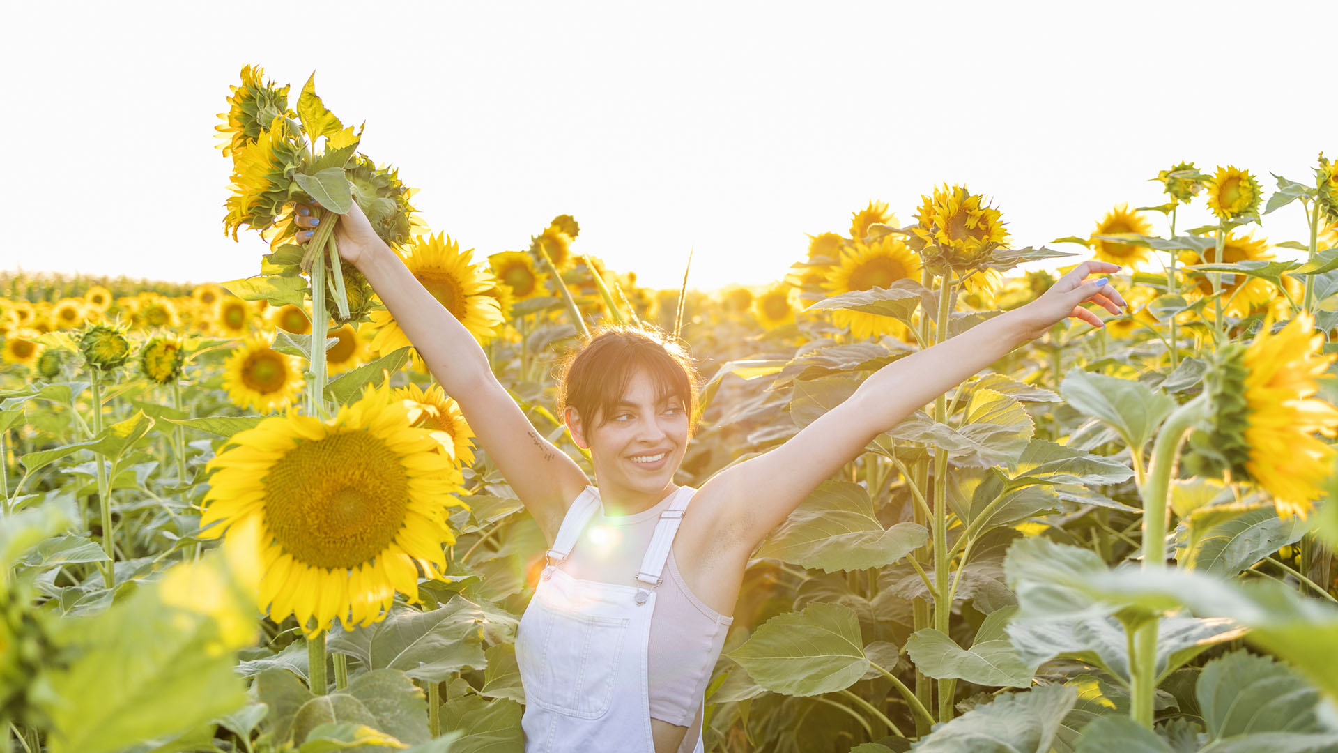 Freedom in a field of sunflowers. The girl happily holds a bouquet of sunflowers in her hands
